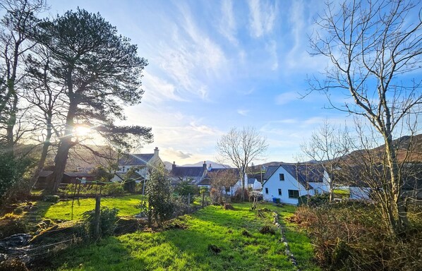 Paisagem rural com casas, um campo gramado e céu claro.