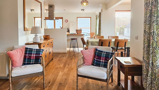 Un salon chaleureux avec une cheminée, des meubles en bois et un coin repas comprenant une table et des chaises.
