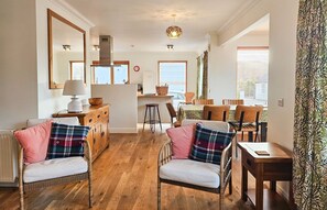 Uma sala de estar aconchegante com lareira, móveis de madeira e um espaço de jantar com mesa e cadeiras.
