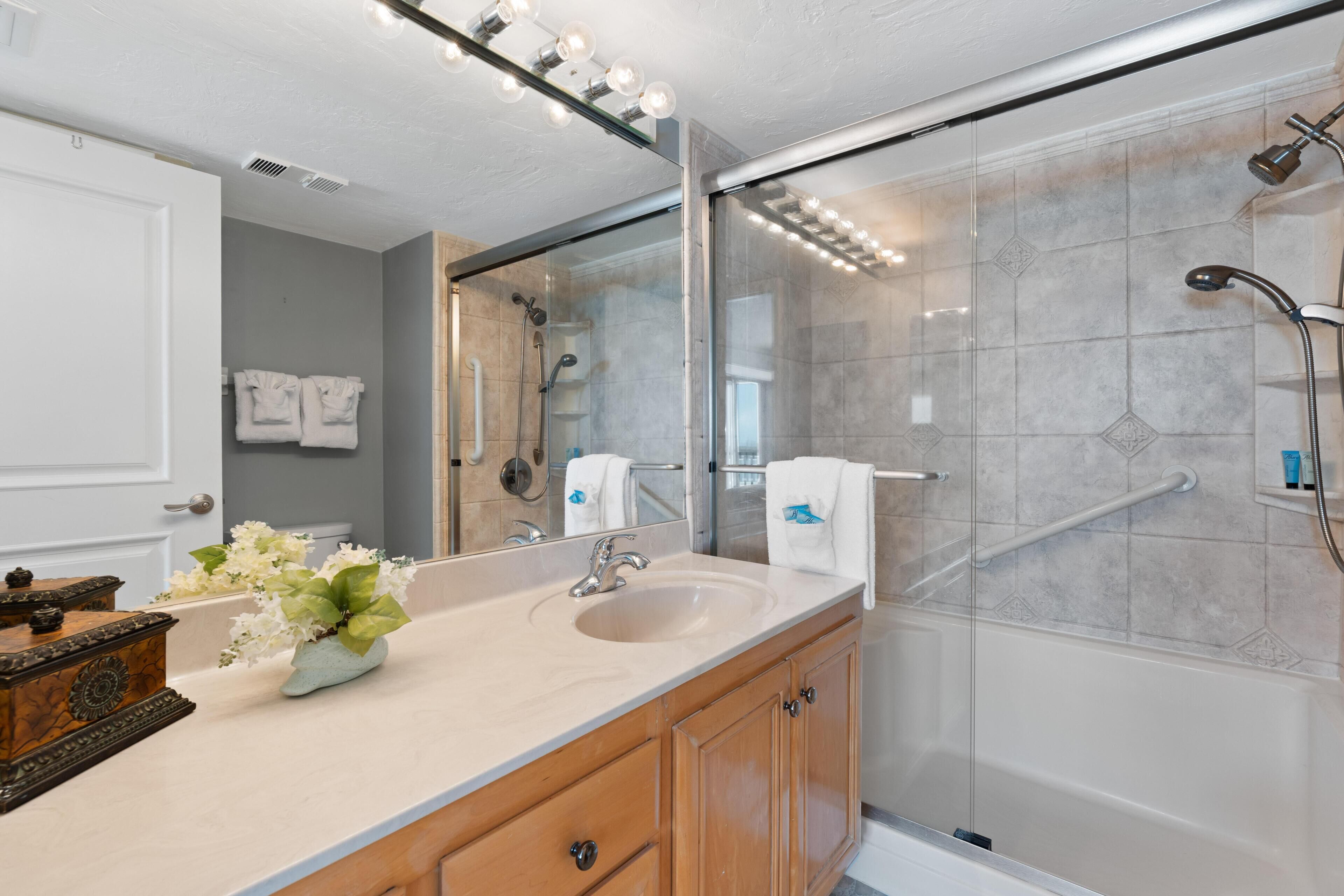 Une salle de bain moderne avec un grand miroir, un lavabo et un espace douche.