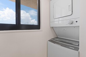 Lavandería con ventana, secadora y lavadora.