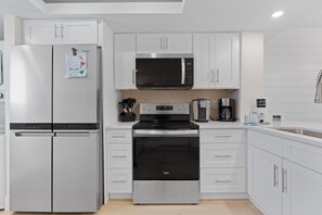 Una cocina moderna con electrodomésticos de acero inoxidable, armarios blancos y horno empotrado.