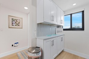 A modern kitchen with white cabinets, a stainless steel sink, and a window with a city view. - Carlos Pointe #231 Beach Bum Getaway (Fort Myers Beach)