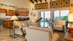 A spacious living area with a kitchen, a balcony with a view, and a ceiling fan. - Cay Syrah! 4 bedroom home! Solar/battery backup! (Cruz Bay)
