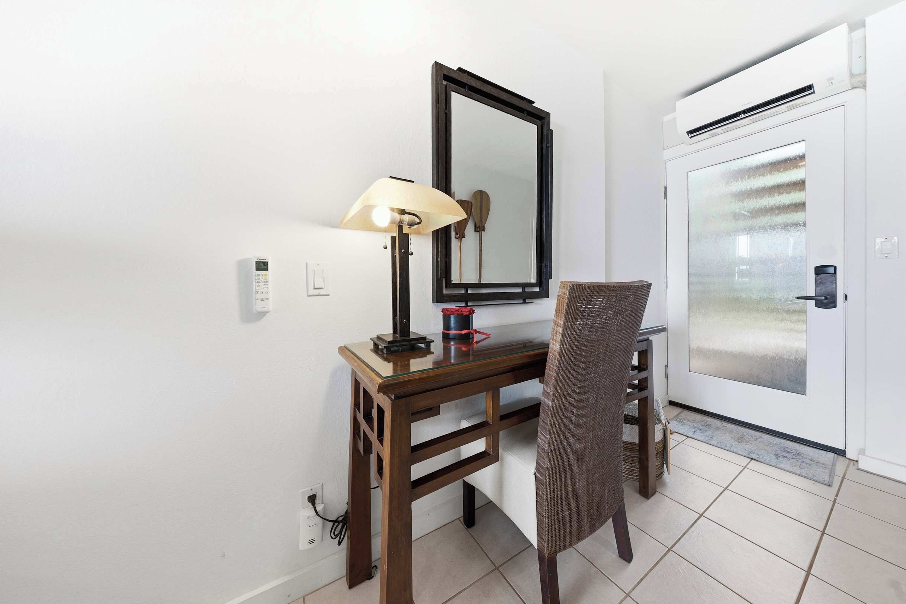 Quarto com escrivaninha, cadeira, abajur, espelho e ar condicionado.