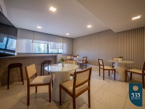 A modern dining area with a round glass table, wooden chairs, and a striped wall. - Caminho das Árvores near the shopping malls (Salvador)