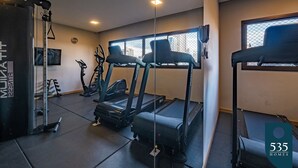 Et fitnesscenter med løbebånd, crosstrainere og et styrkeløftområde.