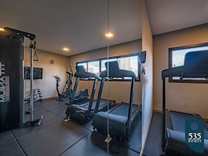 Ein Fitnessstudio mit Laufbändern, Crosstrainern und einer Gewichthebecke.