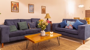 A living room with two sofas, a coffee table, a lamp, and framed artwork on the wall.