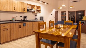 A modern kitchen with wooden cabinets, a dining table, and overhead lighting.
