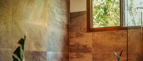 A modern bathroom with a freestanding bathtub, large windows, and a hanging light fixture.