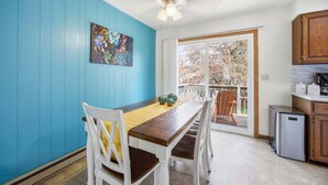 A dining area with a wooden table and chairs, a ceiling fan, and a view through a glass door to the outside. - Family-friendly duplex near Fargodome, kings+bunk (Fargo)