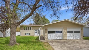A two-story house with a garage, a front door, and a small porch. - Family-friendly duplex near Fargodome, kings+bunk (Fargo)