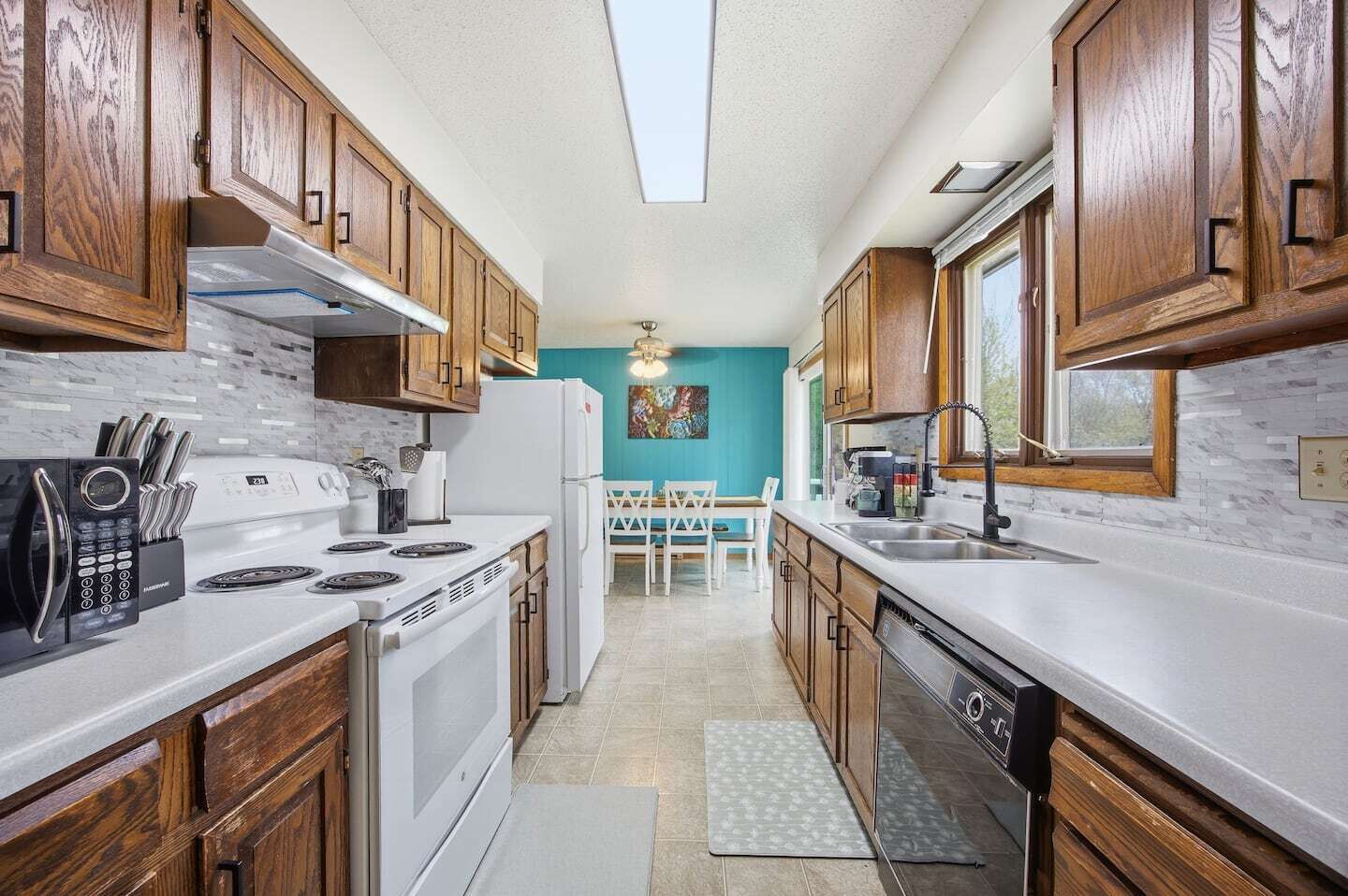 Una cocina con armarios de madera, estufa blanca, microondas y lavavajillas.