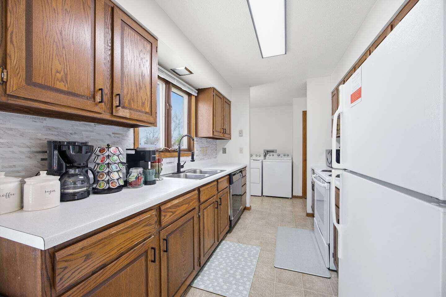A kitchen with wooden cabinets, a coffee maker, a sink, and a refrigerator.