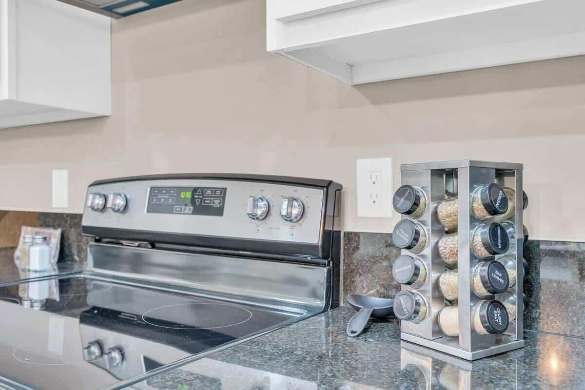 Une cuisine moderne dotée d’une cuisinière en acier inoxydable, d’un plan de travail en verre et d’un porte-épices.