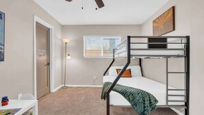A bunk bed room with a ceiling fan, a desk, and a window with blinds. - Midtown Cozy Getaway! (Tucson)