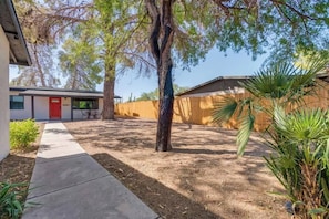 A residential property with a paved driveway, a red door, a wooden fence, and a palm tree. - Midtown Cozy Getaway! (Tucson)