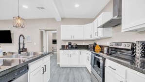 A modern kitchen with white cabinets, a stainless steel range, and a built-in oven. - Midtown Cozy Getaway! (Tucson)