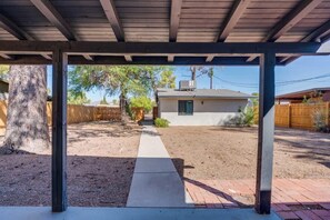 Ein überdachter Patio-Bereich mit einem Pflasterweg, der zu einem Haus führt.