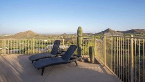 A terrace with two lounge chairs, a cactus, and a view of a desert landscape. - Exquisite Starr Pass Desert Haven with Pool (Tucson)