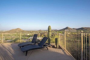 A terrace with two lounge chairs, a cactus, and a view of a desert landscape. - Exquisite Starr Pass Desert Haven with Pool (Tucson)