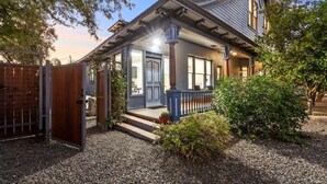 A two-story house with a porch, a wooden gate, and a gravel driveway. - Historic Studio near 4th Ave and U of A (Tucson)