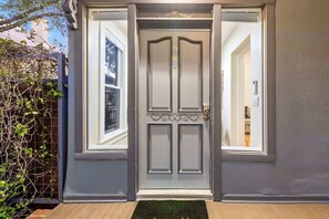 A grey double door with a decorative top, a small window on the left, and a doorbell. - Historic Studio near 4th Ave and U of A (Tucson)