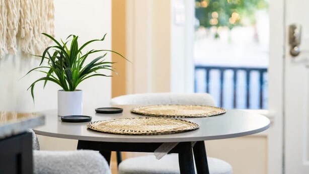 A round table with woven placemats, a potted plant, and a white chair. - Historic Studio near 4th Ave and U of A (Tucson)