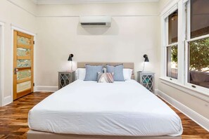 Ein Schlafzimmer mit einem großen Bett, zwei Nachttischen, einer Klimaanlage und einem Fenster mit Blick.