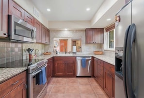 A kitchen with wooden cabinets, stainless steel appliances, and a tiled backsplash. - Southwest Gem-Pool & Mountain Views (Tucson)