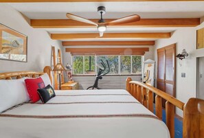 A bedroom with a bed, wooden headboard, a ceiling fan, a window with a view, and a door. - Southwest Gem-Pool & Mountain Views (Tucson)