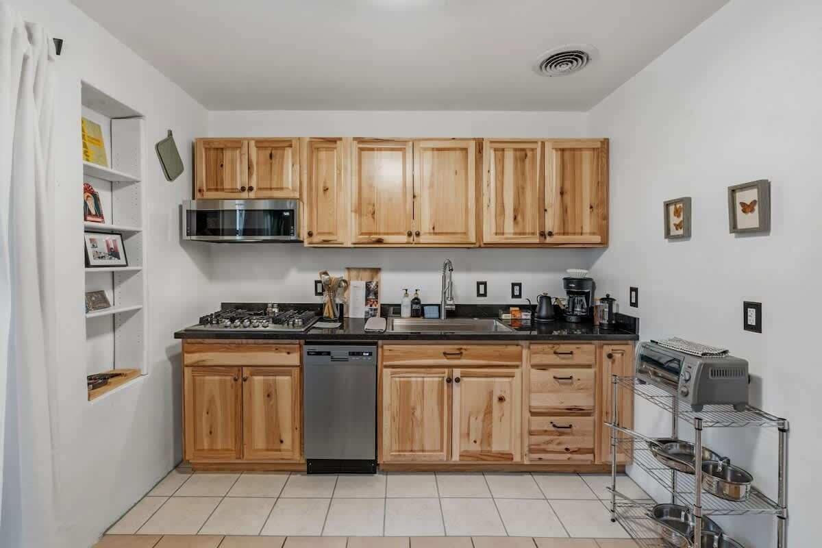 A compact kitchen with wooden cabinets, a dishwasher, a microwave, and a coffee maker.