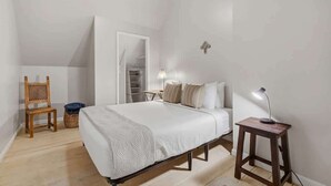 A bedroom with a bed, a chair, a bedside table with a lamp, a closet, and a ceiling fan. - Walkable Barrio Charm (Tucson)