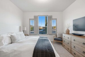 A bedroom with a bed, a TV, a dresser, and a window with shutters. - Exceptional Desert Escape w/ Pool and Spa (Marana)
