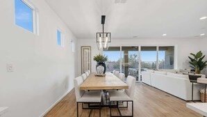 A modern kitchen with a wooden table, white chairs, and a hanging light fixture. - Exceptional Desert Escape w/ Pool and Spa (Marana)