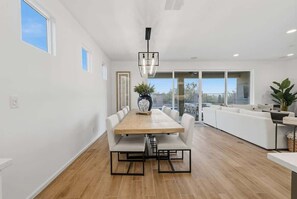 A modern kitchen with a wooden table, white chairs, and a hanging light fixture. - Exceptional Desert Escape w/ Pool and Spa (Marana)