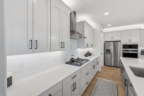 Een moderne keuken met witte kastjes, roestvrijstalen apparatuur en een centraal eiland.