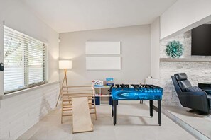 A room with a foosball table, a sofa, a lamp, and a window with blinds. - Spacious Family Getaway-Pet Friendly! (Tucson)