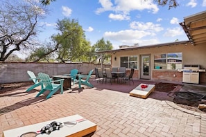 A patio area with outdoor furniture, a barbecue grill, and a brick wall. - Spacious Family Getaway-Pet Friendly! (Tucson)