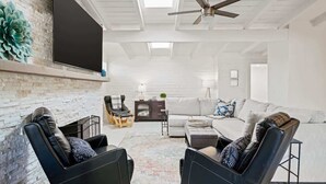 Een moderne woonkamer met een open haard, een flatscreen televisie, een plafondventilator en een bank.