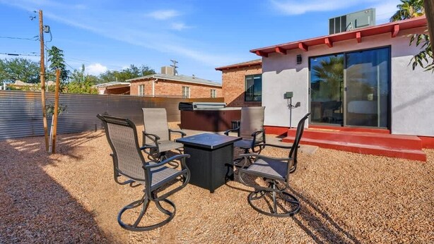 Un patio al aire libre con una mesa y sillas, un edificio de techo rojo y un cielo despejado.