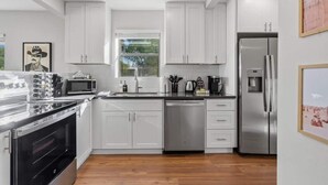 Una cocina moderna con gabinetes blancos, electrodomésticos de acero inoxidable y suelo de madera.