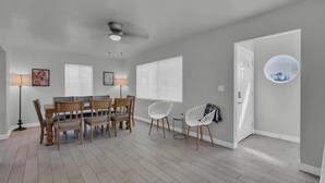 Ein Essbereich mit Tisch und Stühlen, einem Deckenventilator und einer Tür mit rundem Fenster.