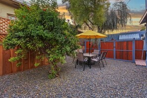 Une terrasse avec une table et des chaises, un parasol jaune et une clôture en bois.