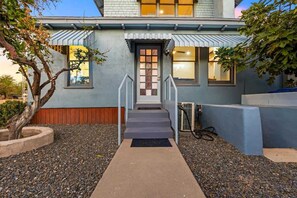 Une maison moderne avec une entrée à l’avant, des marches et un petit jardin.