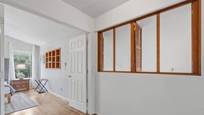 A hallway with wooden flooring, white walls, and a large window with blinds. - Bright & Spacious Family Retreat (Tucson)