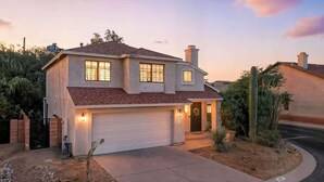A two-story house with a garage, a driveway, and a landscaped front yard with cacti. - Bright & Spacious Family Retreat (Tucson)