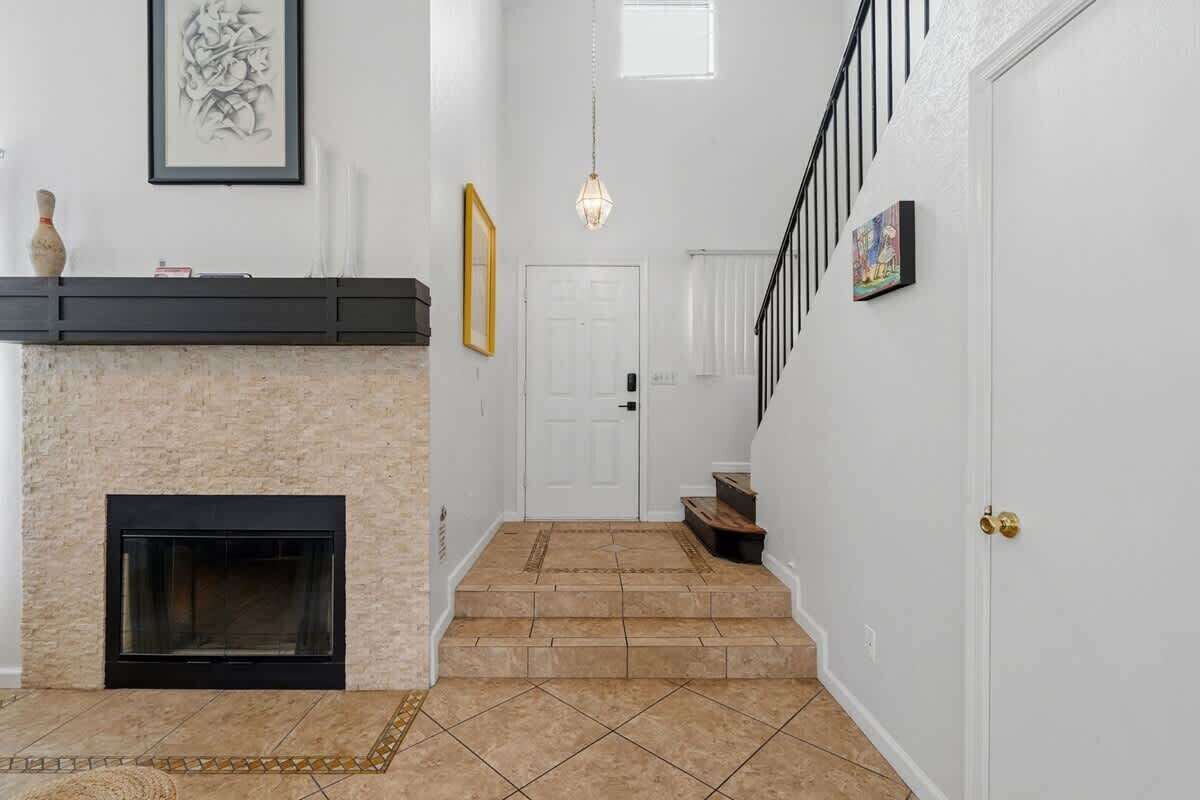 A staircase leading to a door, a fireplace, and a wall-mounted light fixture.