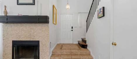 A staircase leading to a door, a fireplace, and a wall-mounted light fixture.